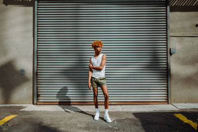 Stylish teenager with curly hair and makeup posing on the street