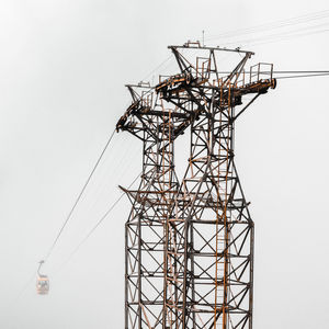 Low angle view of electricity pylon against clear sky
