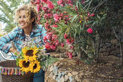 Portrait of young woman standing amidst flowers