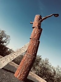 Low angle view of cross on tree trunk against sky