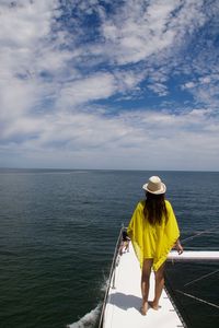 Woman standing on boat sailing in sea against sky