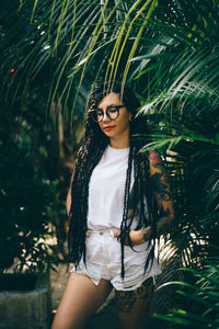 Young woman standing by trees