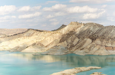 Scenic view of rock by lake against sky