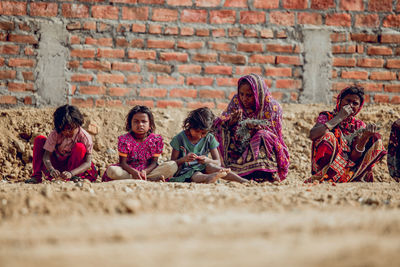 Group of people sitting on stone wall