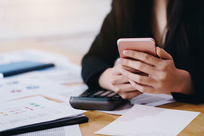 Midsection of woman using smart phone on table