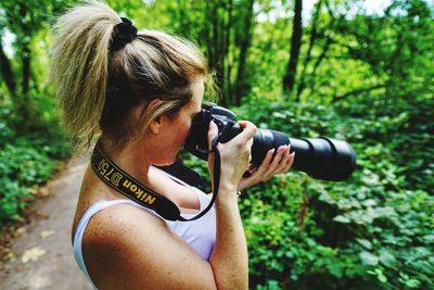 Midsection of woman photographing in forest