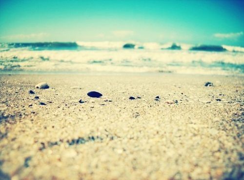 beach, sand, surface level, sea, shore, selective focus, sky, tranquility, nature, tranquil scene, pebble, scenics, beauty in nature, blue, horizon over water, water, outdoors, no people, close-up, idyllic