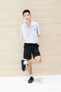 Portrait of young man sitting against wall