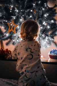 Rear view of boy looking at christmas decoration at home