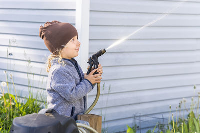 Side view of boy holding water hose
