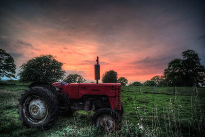 Tractor on field against sky during sunset