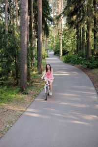 Rear view of man riding bicycle on road in forest