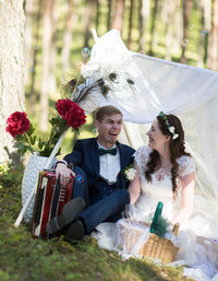 Cheerful newlywed couple sitting in park