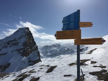 Information sign on snowcapped mountains against sky