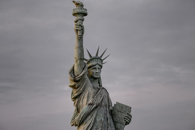 Low angle view of statue of liberty against cloudy sky