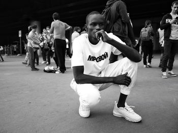 Thoughtful young man crouching on street at dusk