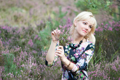 Young woman looking away while holding flowers 