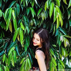 Smiling woman standing against tree