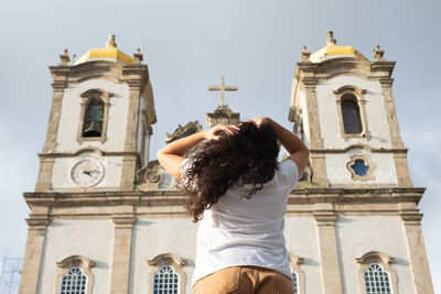 Rear view of woman standing against historic church