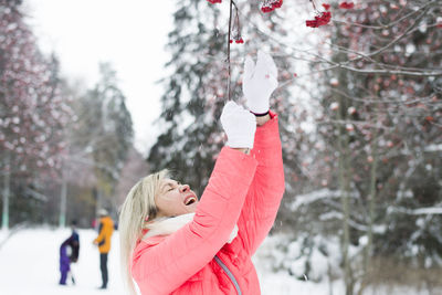 Woman reaching viburnum berries on tree