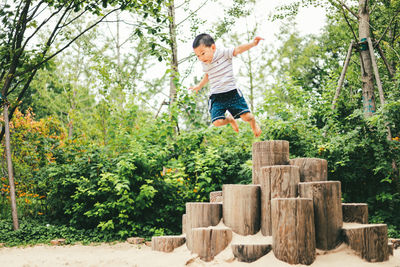 Full length of boy jumping against trees