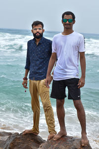 Full length of friends standing on beach