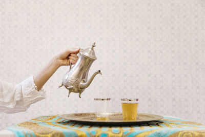 Close-up of hand holding drink on table