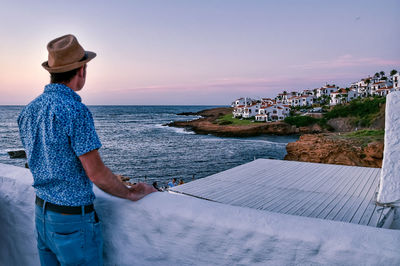 Man standing by sea against sky during sunset