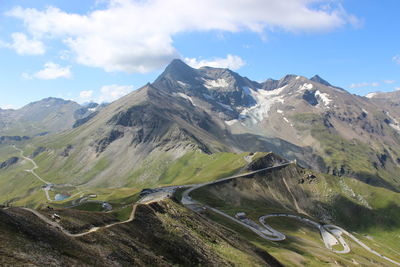 Scenic view of winding road in the mountains against cloudy sky