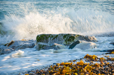 Scenic view of waves splashing on rocks at beach