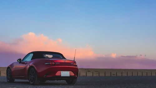 Car on sea against sky during sunset