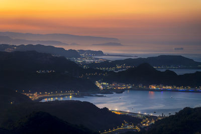 High angle view of illuminated city against sky during sunset