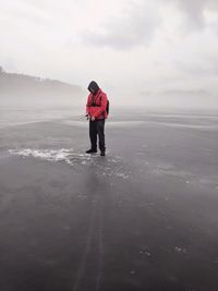 Man standing at frozen sea against sky