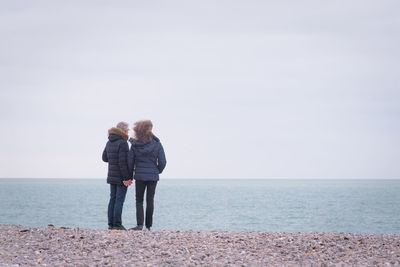 Rear view of couple standing by sea against sky