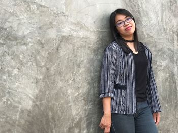 Young woman standing against wall