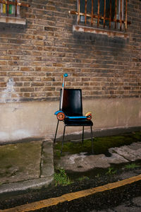 Empty chair against brick wall