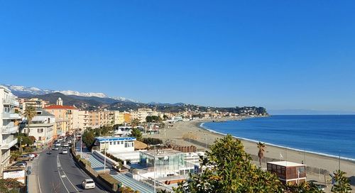 High angle view of buildings by sea against clear blue sky