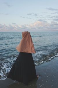 Rear view of woman on beach against sky