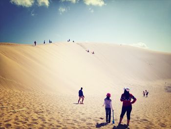 People at desert against sky