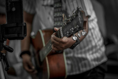 Midsection of man playing guitar