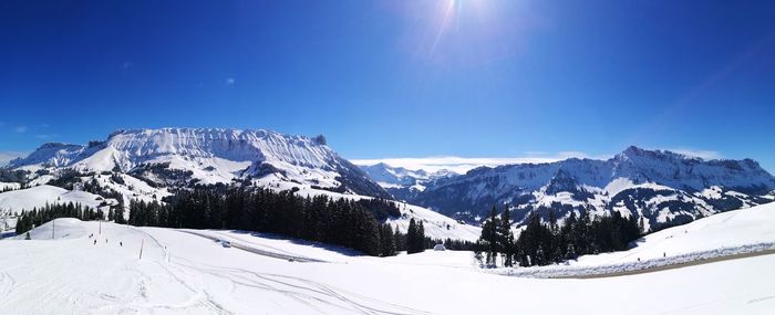 Scenic view of snow covered mountains against blue sky