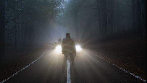 Rear view of man walking on road at night