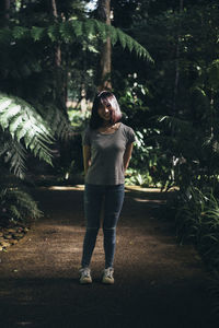 Portrait of young woman standing against trees