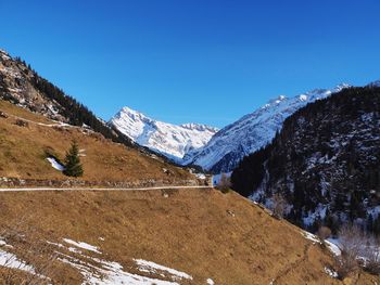 Scenic view of snowcapped mountains against clear blue sky