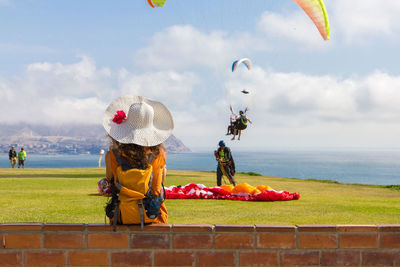 Paragliding on landscape against clouds