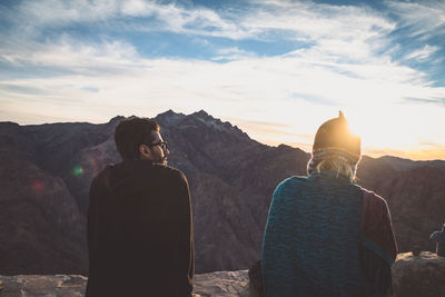 Rear view of people looking at mountains against sky