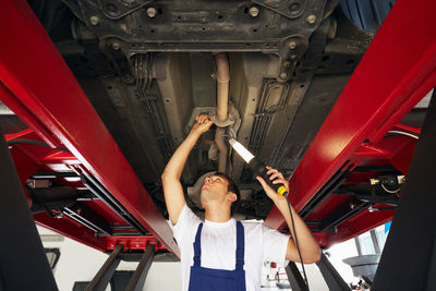 Low angle view of mechanic repairing car in garage