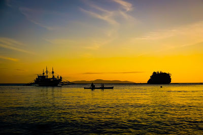 Silhouette boats in sea against sky during sunset