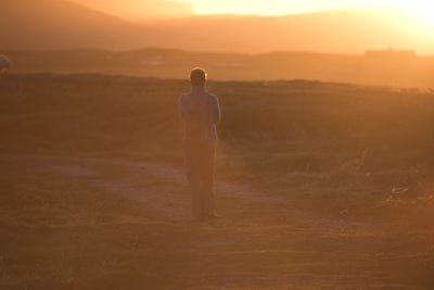 Rear view of man walking on field