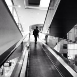 Rear view of woman walking on escalator